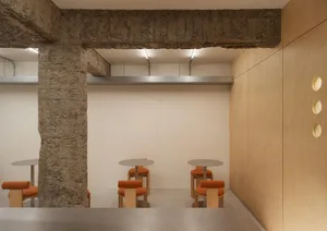 An empty restaurant interior with wooden tables and orange cushioned chairs, creating a warm and inviting atmosphere