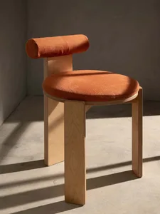 A dimly lit room with a wooden floor and an orange chair with a cushion, creating a cozy atmosphere