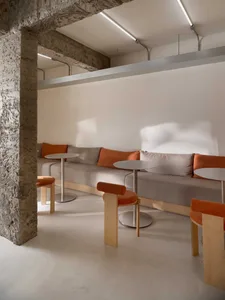 A cozy living space with two couches, chairs, and multiple dining tables, creating a warm and inviting atmosphere