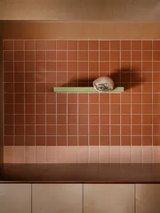 Cozy kitchen space with a tile wall, a wooden-handled hat, and a glass bowl on a shelf, with a functional and inviting atmosphere