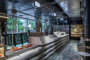 Busy modern restaurant with a counter, glass partitions, and natural light