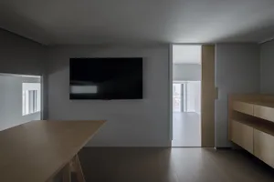Empty living room with a flat screen TV, wooden floors, and good lighting
