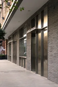 Modern building facade with a brick exterior, glass door, and large windows providing natural light