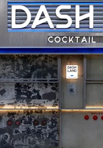Exterior view of a modern restaurant with a gray and white facade, red accents, and bottles on the ground, taken during the daytime