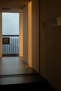 透過窗戶可見帶陽台與金屬扶手的昏暗房間內部景觀