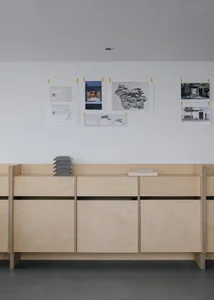 A professional office space with pinned architectural plans and books on the wall