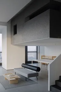 Open modern living area with a couch, chairs, dining table, and bench, surrounded by natural light and minimal decor