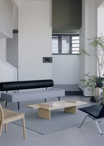 Open modern living area with a large couch, two chairs, a dining table, and a potted plant, featuring a comfortable and inviting atmosphere