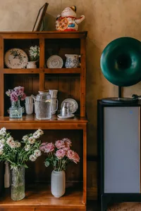 A warm and inviting living area with a wooden bookshelf featuring various decorative items, books, and vases