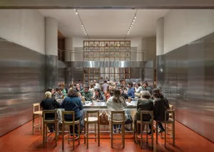 A lively indoor dining area with multiple tables and chairs, handbags on some chairs, and patrons enjoying their meals in a casual and inviting atmosphere