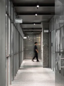 A modern hotel lobby with a silver metal finish, featuring two individuals walking down the hallway