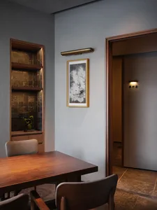 Modern living area with a wooden dining table, chairs, and a doorway leading to another part of the house