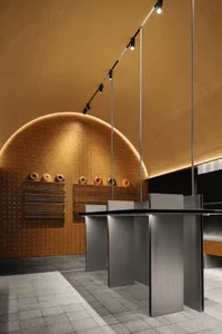 A modern interior design showroom with a large round metal table surrounded by wooden chairs in a welcoming atmosphere