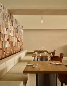 Cozy modern restaurant interior with wooden tables, chairs, and a couch, featuring wine glasses and cups