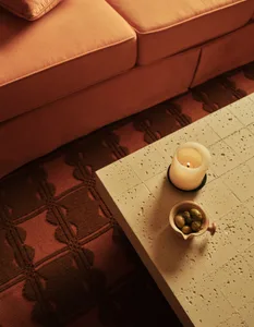 A warm and inviting living space with an orange couch, a white table, and two candles creating a cozy atmosphere