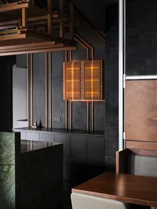 A kitchen with wooden cabinets and tables, black countertops, and a sink, set against a neutral background