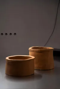 Two brown clay vases on a table in a dimly lit room create a calm and serene atmosphere