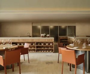Inviting kitchen with wooden floors and walls, featuring a dining table with chairs and wine glasses, and various kitchen items scattered throughout
