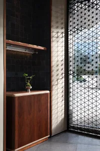 A wooden cabinet with a potted plant on top, surrounded by vases and a view of a car through a window