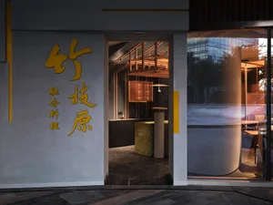 A modern Asian restaurant with a large window, two dining tables, and a vase, creating an inviting and comfortable atmosphere