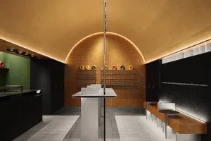 Modern showroom with a round room, central island counter, tables, benches, and decorative elements in brown and white tones, with unique wall pattern and warm lighting