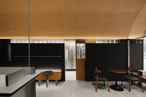 Warm and inviting restaurant interior with wooden floors and walls, featuring tables and chairs, a refrigerator, and a comfortable dining area