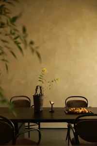 Warm and inviting dining area with a wooden table, chairs, and a vase, creating a cozy atmosphere