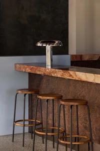 A modern bar with a marble countertop and wooden stools, inviting and comfortable atmosphere for socializing and enjoying drinks