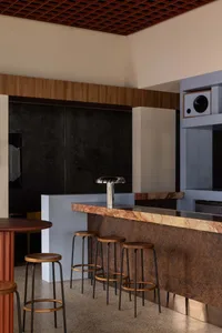 Modern kitchen and dining area with a marble bar, stools, chairs, and a sink, featuring a sophisticated design and elegant style