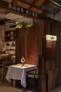Warm and inviting dining space with wooden walls, tables, and chairs, featuring traditional Asian design elements and potted plants