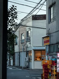 寧靜的城市街角，設有現代咖啡店，以白色立面、混凝土與玻璃材質為特色，背後襯托兩棟建築