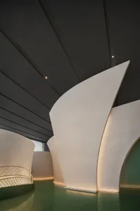 A modern interior space with a curved white wall, two doorways, and a minimalist aesthetic