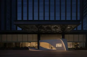 A modern art installation at night with a glass exterior, featuring two people observing the unique design