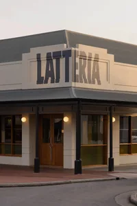 A modern restaurant exterior with a white facade, black accents, and natural light entering through several windows