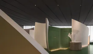 A modern interior design showroom with a large green door, white walls, and well-lit space, possibly with natural and artificial lighting