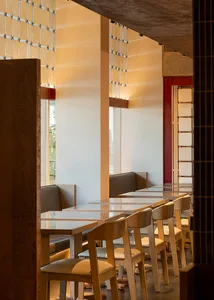 Modern restaurant dining area with glass tables, white walls, and dim lighting creating a cozy atmosphere