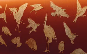 A colorful arrangement of metal birds in various poses and sizes on an orange background, creating a dynamic display