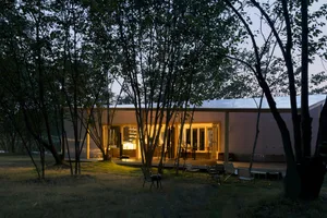 Open living area with wood flooring, a dining table, and multiple chairs, featuring a relaxed and inviting atmosphere