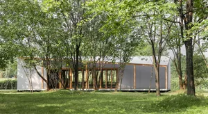 環繞樹木的露天建築，現代設計擁有大片窗戶、木構結構與寧靜氛圍