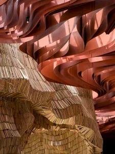 A creative library interior featuring a spiral staircase constructed from books, surrounded by bookshelves and a cozy atmosphere