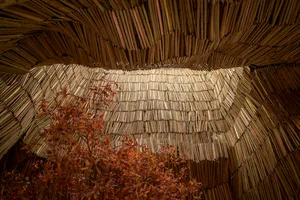 A cozy interior space with wooden walls, wooden floors, and scattered books, creating a warm and inviting atmosphere