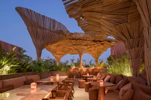 A restaurant patio with wooden structures, thatched roofs, and potted plants, creating a warm and inviting atmosphere for dining and socializing