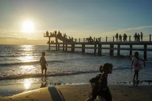 A relaxed beach scene at sunset with people enjoying the ocean view