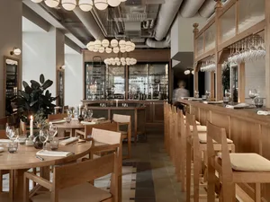 A cozy restaurant dining area with wooden tables and chairs, wine glasses, and an inviting atmosphere