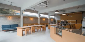 Open modern restaurant interior with wooden tables and chairs, comfortable seating for guests, and ample dining space
