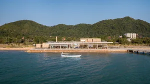 A beachside restaurant with a large open dining area, featuring various chairs and a scenic ocean view