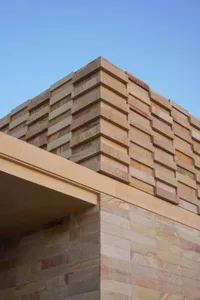一座建築立面，擁有大型磚牆並帶有石材紋理與色調，展現現代與傳統元素的混搭，多層樓層設有多個窗戶