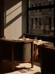 Sophisticated restaurant interior with multiple tables, chairs, and wine glasses, set in a well-lit and inviting space