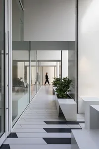 A calm and inviting lobby with glass doors, potted plants, and two benches