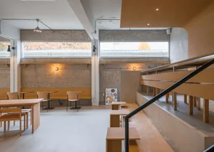 A restaurant interior with wooden floors and walls, featuring dining tables and chairs, creating a warm and inviting atmosphere
